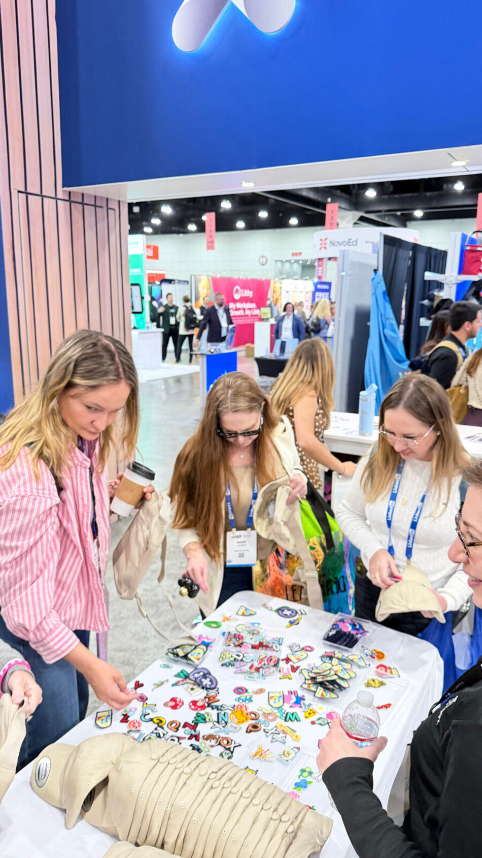 Guests gathered around a table choosing from a colorful spread of iron-on patches at a live customization bar